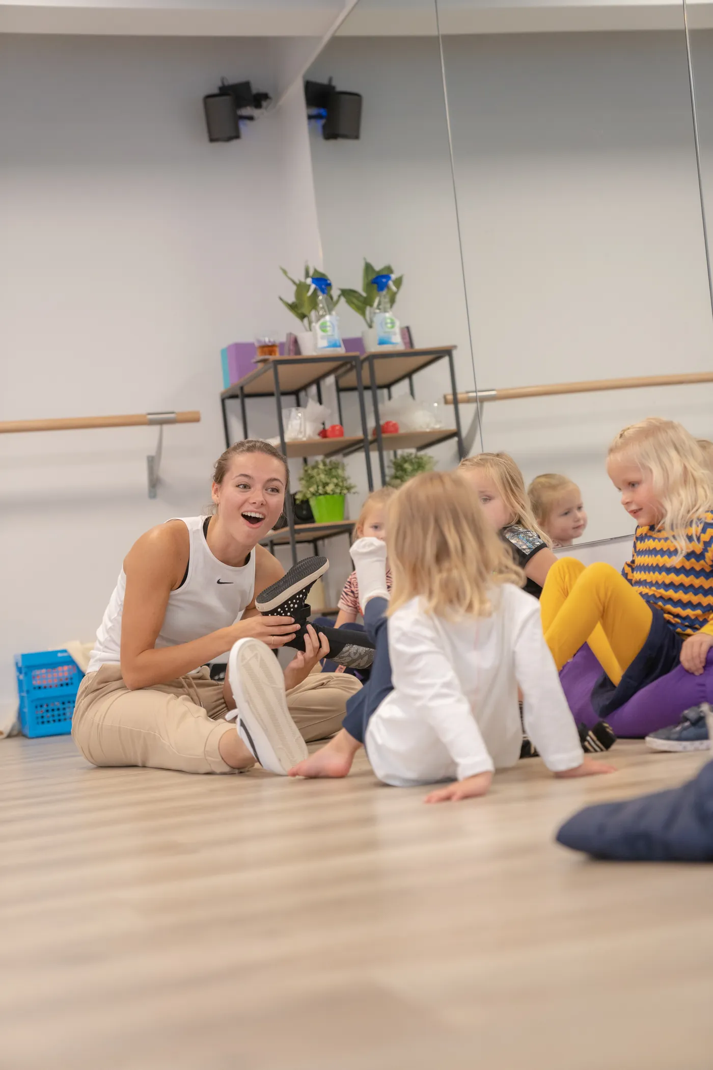 Julia zit op de vloer van de studio tussen een groep lachende kleuters