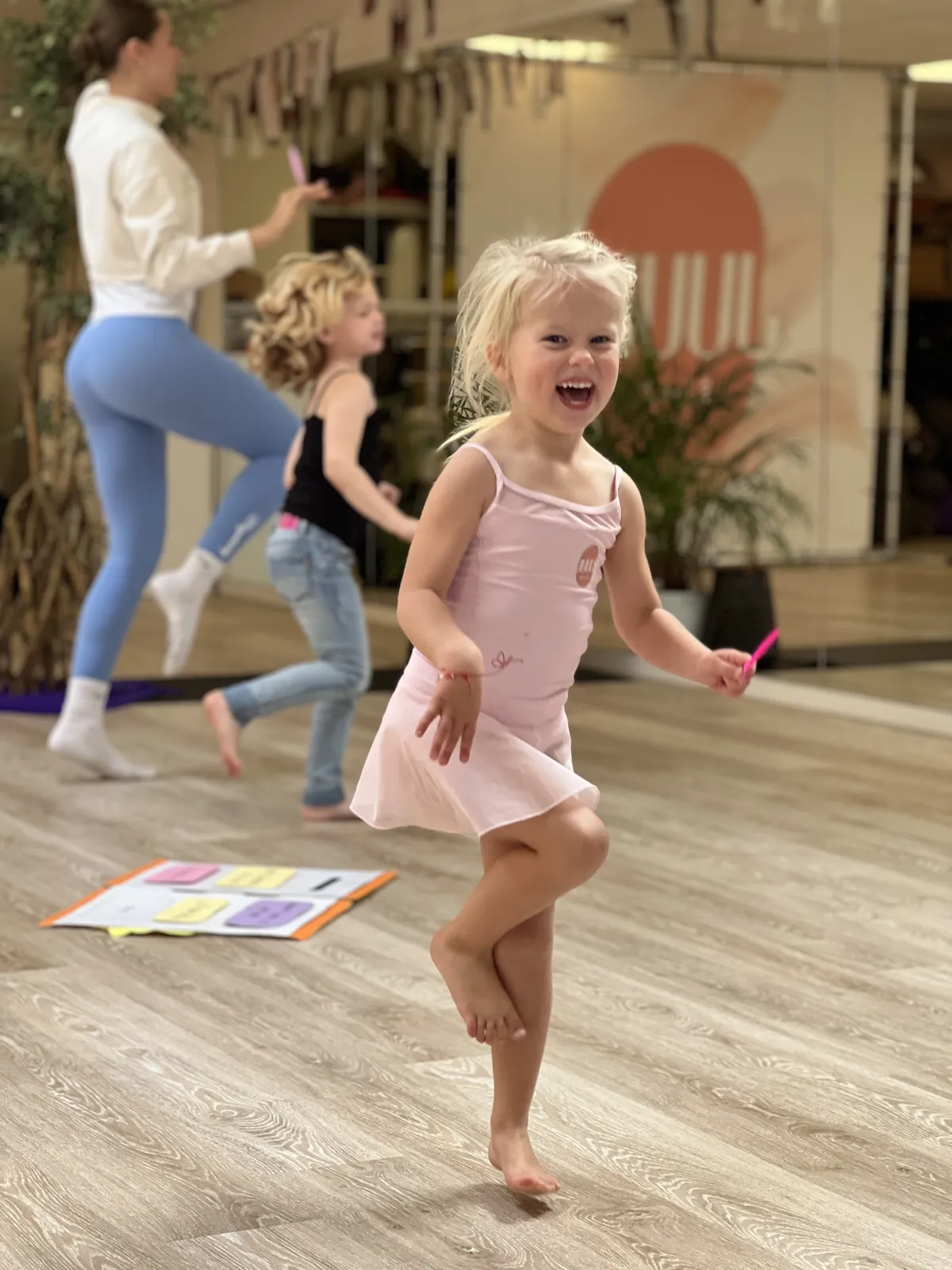 Een lachend meisje in een roze balletpakje springt in de studio